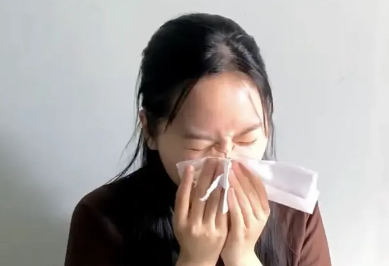 Tâm holding a tissue to her nose