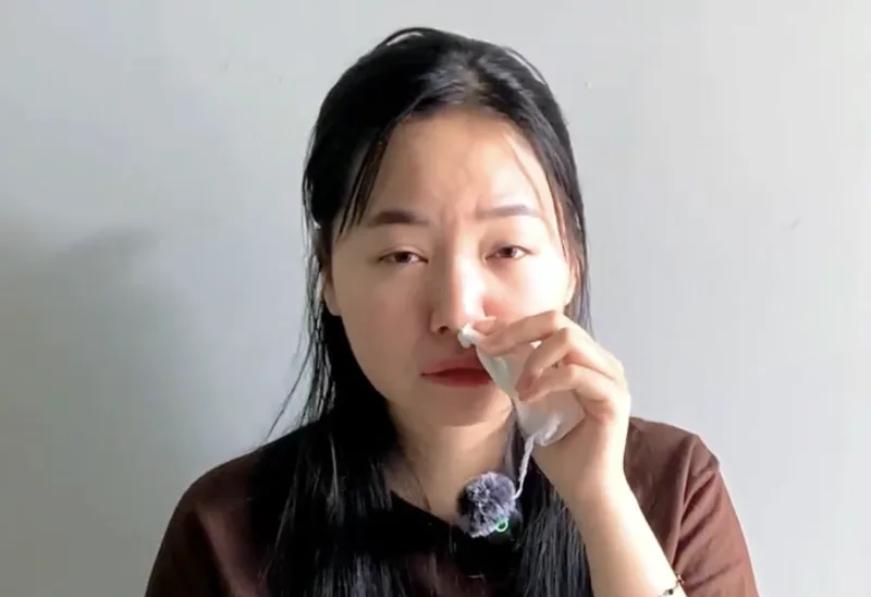 Tâm holding a tissue to her nose